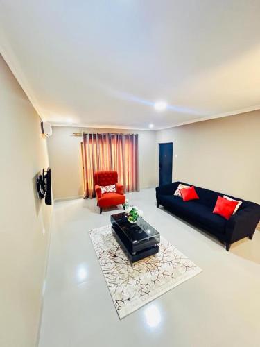 ein Wohnzimmer mit einem Sofa und einem roten Stuhl in der Unterkunft Goldland Apartments Annex in Kitwe