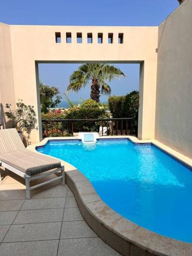 a swimming pool with a bench next to a building at Villa with 2 Bedrooms Sea View and Garden with private Pool in Ras al Khaimah