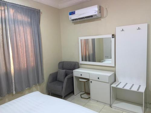 a room with a bed and a chair and a mirror at الفخامة الجنوبية للشقق المخدومة in Jazan