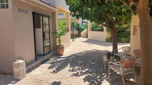 a patio with chairs and a tree next to a building at Miramar Complex - Korfos in Korfos