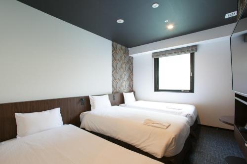 2 camas en una habitación pequeña con ventana en Henn na Hotel Tokyo Akasaka, en Tokio