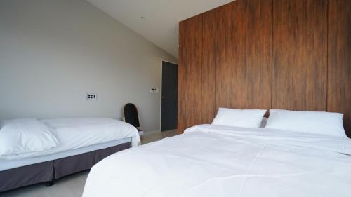 a bedroom with two beds and a wooden headboard at Byeonsan Stay 365 in Buan