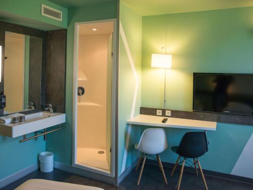 アルシャンにあるIbis Budget Archamps Porte de Genèveのバスルーム(シンク、鏡、椅子2脚付)