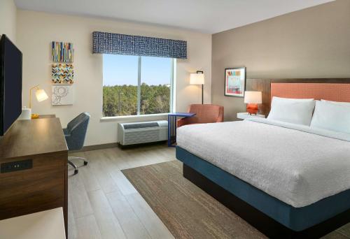 ein Hotelzimmer mit einem Bett, einem Schreibtisch und einem Fenster in der Unterkunft Hampton Inn & Suites Fultondale Birmingham I 65, Al in Fultondale