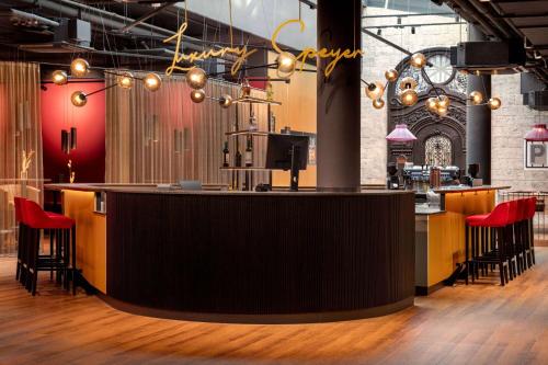 a bar in a restaurant with red chairs and a counter at Amedia Plaza Speyer, Trademark Collection by Wyndham in Speyer