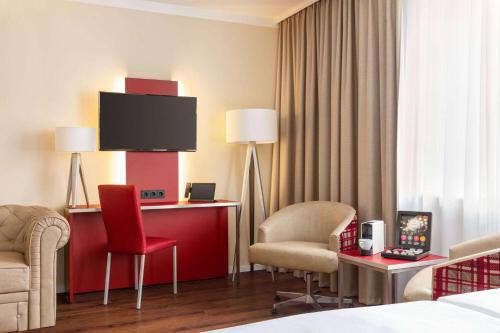 a hotel room with two chairs and a flat screen tv at Amedia Plaza Speyer, Trademark Collection by Wyndham in Speyer
