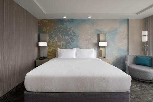 um quarto com uma grande cama branca e uma cadeira em Courtyard by Marriott Edina Bloomington em Bloomington