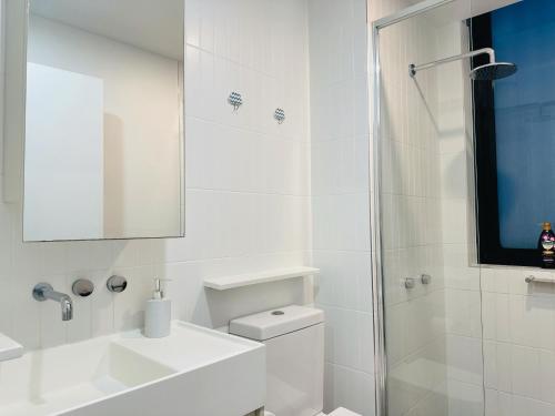 La salle de bains blanche est pourvue d'un lavabo et d'une douche. dans l'établissement Cityscape Oasis Homes at Toowong Precinct, à Brisbane