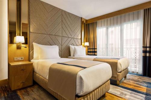 a hotel room with two beds and a window at Days Inn by Wyndham Istanbul Bomonti in Istanbul