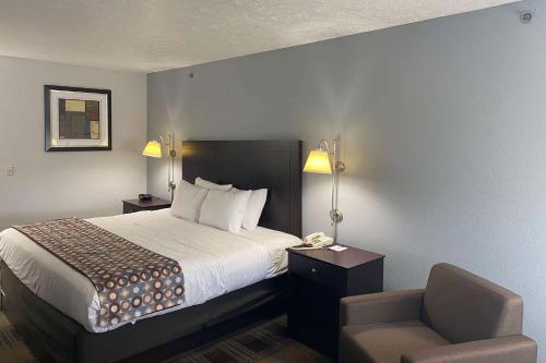 um quarto de hotel com uma cama e uma cadeira em Baymont by Wyndham Danville IL em Danville