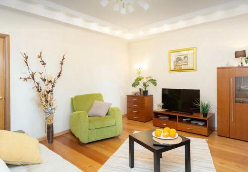 ein Wohnzimmer mit einem grünen Stuhl und einem TV in der Unterkunft VIP apart 732 in Tbilisi City