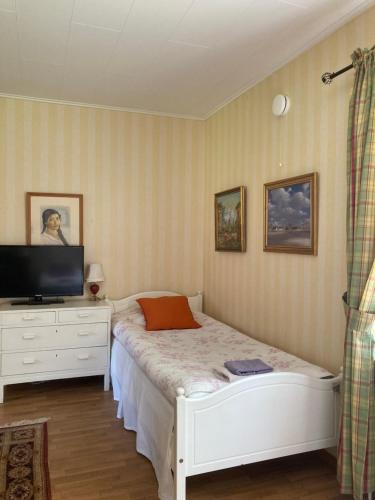 a bedroom with a white bed and a television at Klaraborg - Rum och kök i Borgvik in Borgvik