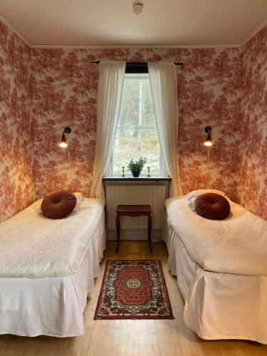two beds in a room with a window at Klaraborg - Rum och kök i Borgvik in Borgvik