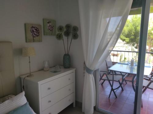 1 dormitorio con vestidor, mesa y balcón en Luz de Tropicana en La Herradura