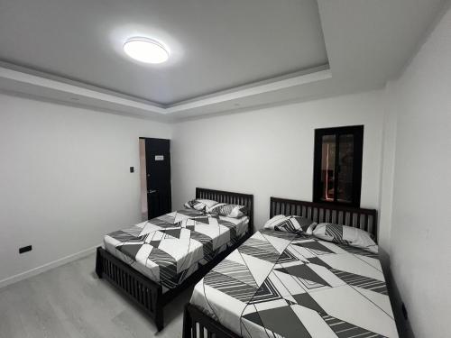 2 Betten in einem Zimmer mit weißen Wänden in der Unterkunft Cozy Haven in Manila