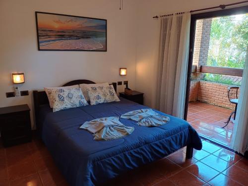 a bedroom with a bed with blue sheets and a window at Solar das Canoas Prumirim in Ubatuba