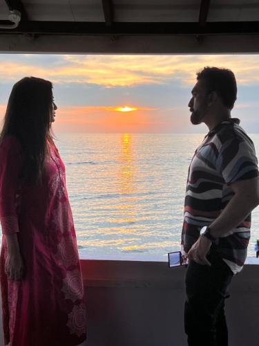 mężczyzna i kobieta stojący przed oknem w obiekcie Ocean View w mieście Kollam