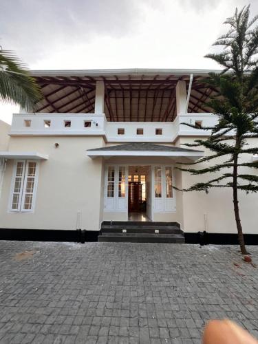 Biały dom z palmą przed nim w obiekcie Ocean View w mieście Kollam