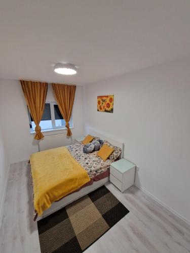 a bedroom with a bed with a yellow blanket and a rug at Vila 12 in Cornetu
