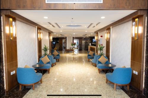 a corridor of a hotel lobby with blue chairs and tables at Sweet Home For Serviced Accommodation in Jeddah