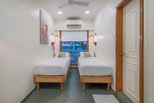 two beds in a room with a window at Hotel Kemps Corner in Mumbai