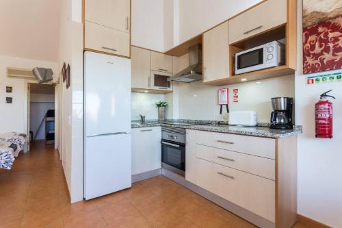 a kitchen with white cabinets and a white refrigerator at Terrace Flat with Magnificient view in Tavira