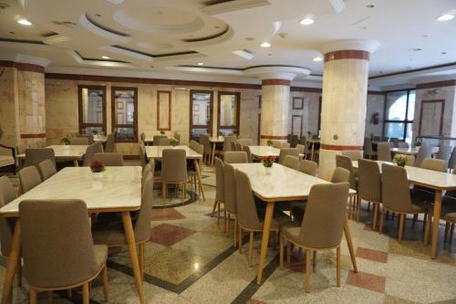 Roaa Al Andalus Hotel فندق رؤى الاندلس في المدينة المنورة: مطعم فيه طاولات وكراسي في الغرفة