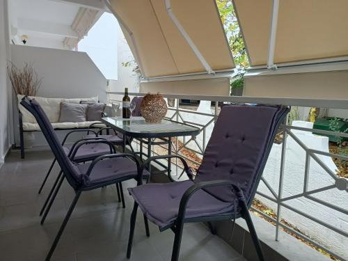 a balcony with purple chairs and a table at Stefiniki Apartment in Psakoudia