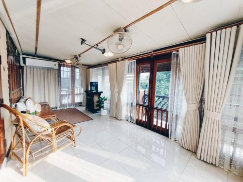 a living room with a chair and large windows at Green Riverside Homestay in Phra Nakhon Si Ayutthaya
