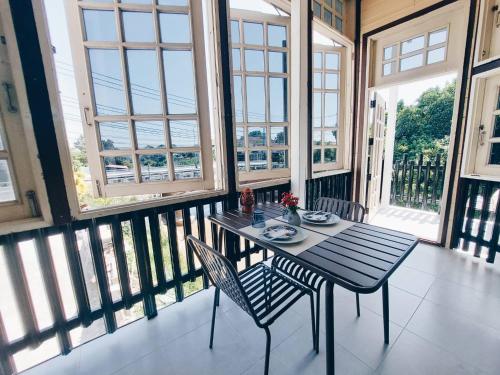 a table and chairs in a room with windows at Green Riverside Homestay in Phra Nakhon Si Ayutthaya
