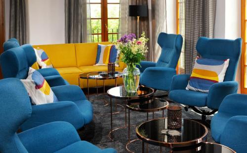 a living room with blue chairs and a yellow couch at Sattlerhof Genießerhotel & Weingut in Gamlitz