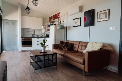 a living room with a brown couch and a kitchen at Zima Edge in Parekklisha