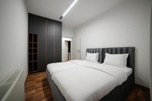 a bedroom with a large white bed with a black headboard at Emery Apartments in Pristina