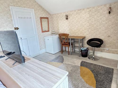 uma sala de estar com uma mesa, um frigorífico e uma porta em Chambre em Montceau-les-Mines