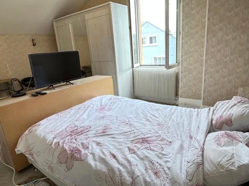um quarto com uma cama e uma televisão de ecrã plano em Chambre em Montceau-les-Mines
