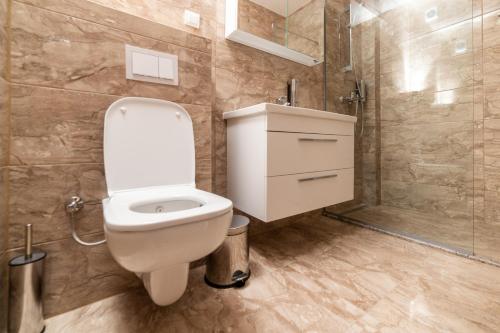 a bathroom with a white toilet and a shower at Emery Apartments in Pristina