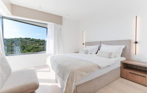 ein weißes Schlafzimmer mit einem großen Fenster und einem Bett in der Unterkunft 4 Bedroom Stunning Home In Murter in Murter