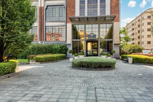 a building with a courtyard in front of it at Italiana Hotels Milan Rho Fair in Rho