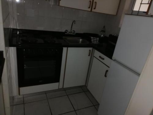 a kitchen with a black stove and a sink at 15 uvongo square holiday home in Margate