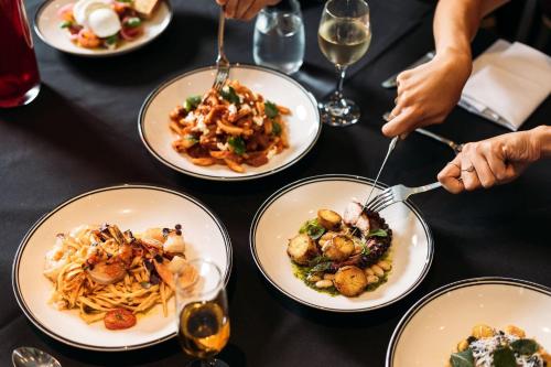 a table full of plates of food with people eating at Crowne Plaza Canberra by IHG in Canberra