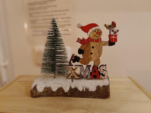 Eine Santa Claus-Figur auf einem Tisch mit einem Weihnachtsbaum in der Unterkunft Le Chant des Vagues in Audinghen
