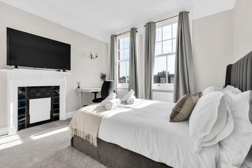 um quarto branco com uma cama grande e uma televisão de ecrã plano em Luxury 3 bedroom apartment in the heart of High Street Kensington, London. em Londres