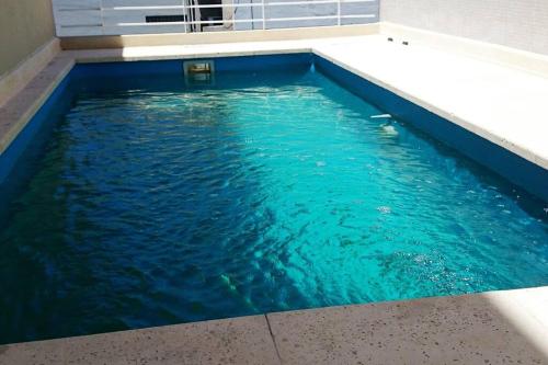a swimming pool with blue water in a building at Cambacuá La Rural in Buenos Aires