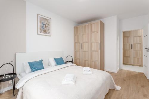a white bedroom with a large white bed with blue pillows at Warsaw City Family Premium in Warsaw