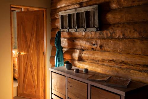 a room with a wooden wall with a table and a door at Pueblo Alto Lodge in Parque Nacional Los Alerces