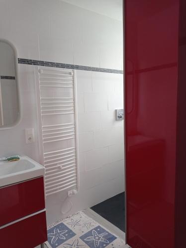 La salle de bains est pourvue d'un lavabo blanc et d'une porte rouge. dans l'établissement Maison de vacances très agréable LA BAULE, à La Baule