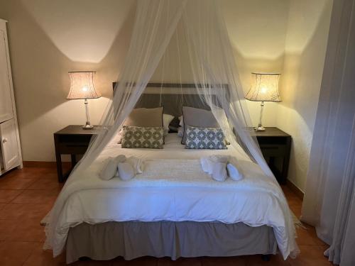 1 dormitorio con 1 cama blanca y 2 lámparas en Haze Inn Cottage, en Henburg Park