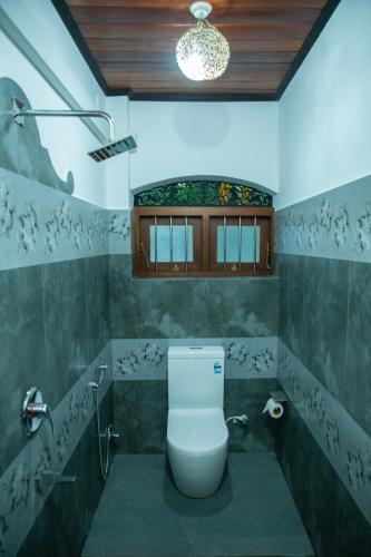 a bathroom with a white toilet in a room at Sea Turtles Bungalow in Bentota