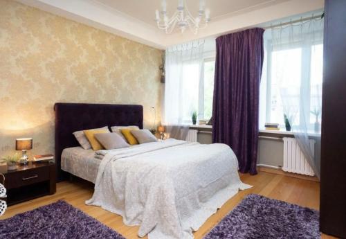 a bedroom with a large bed with purple curtains at VIP apart 741 in Tbilisi City