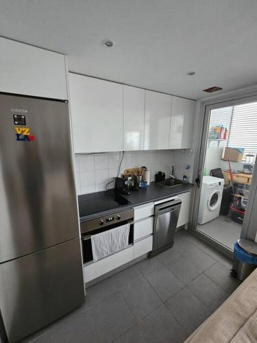uma cozinha com armários brancos e um frigorífico de aço inoxidável em Cómodo apartamento en Madrid em Madrid